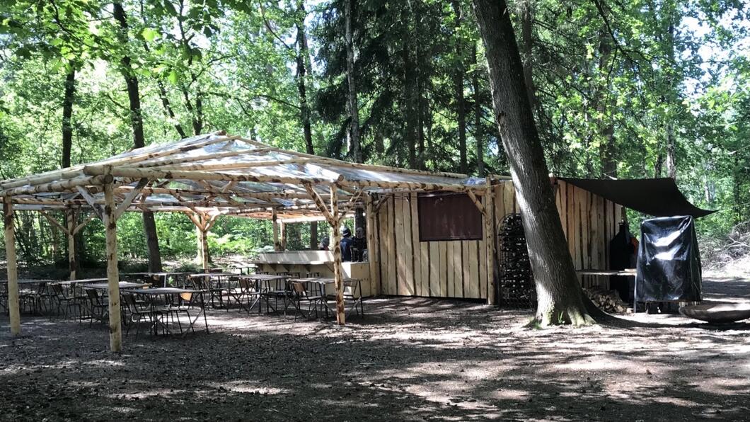Bouwsel van hout met grote overkapping in bosrijk gebied