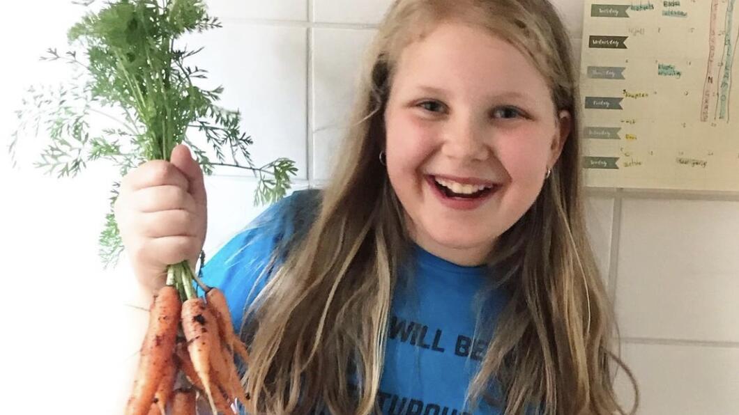 Meisje met bos wortelen, vers uit de tuin