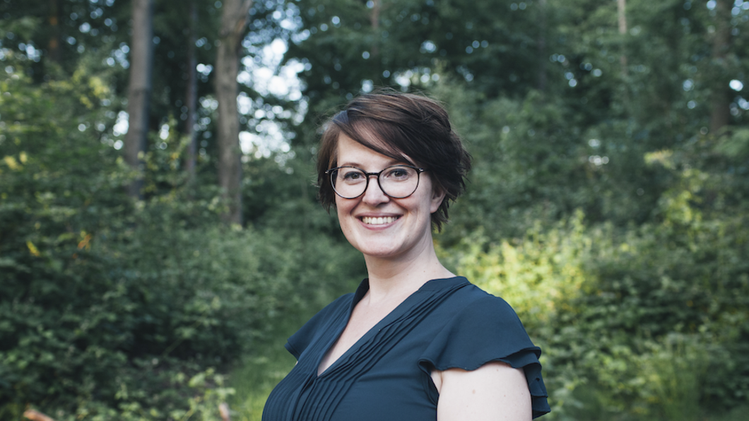 Portret van Eveline Vink, bos op de achtergrond