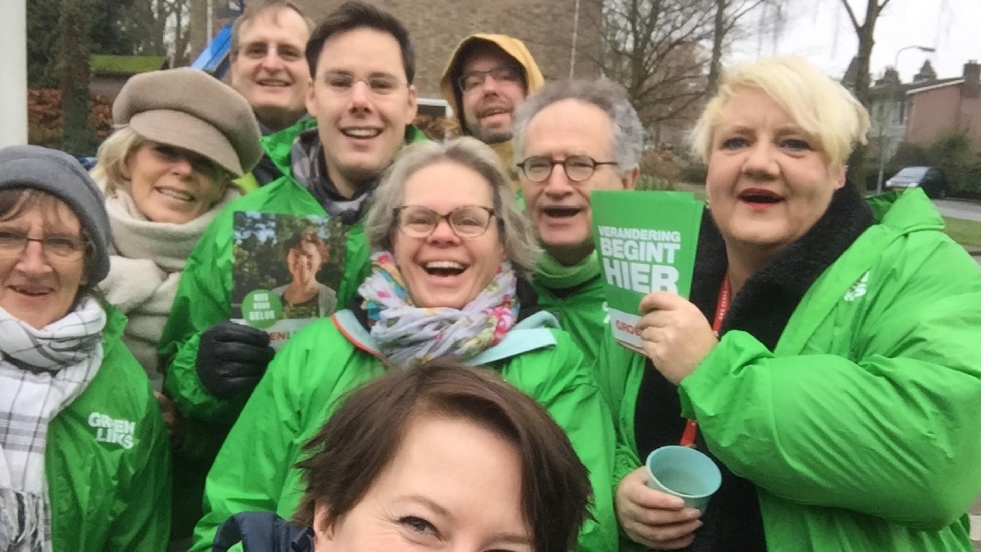 Groepsselfie van blije flyerende mensen in groene jasjes